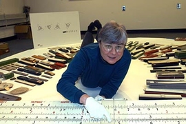 Deborah Douglas, curator of science and technology for the MIT Museum, sprawls among some of the 600 historic slide rules that were recently donated to the museum.