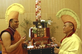 Adorned with hats to show discipleship, MIT Chaplain Tenzin L.S. Priyadarshi, left, and Lama Dhondup Tsering ring ceremonial bells representing compassion at Simmons Hall Monday in the room where the sand mandala is on display.