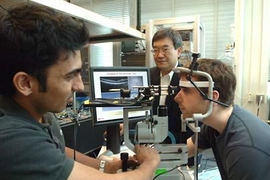 Professor James Fujimoto, center, with students using the eye-imaging technique he began developing in the early 1990s. With his head in the apparatus is Desmond C. Adler and at left, taking measurements, is Vivek Srinivasan. Adler and Sriinivasan are both graduate students in electrical engineering and computer science.