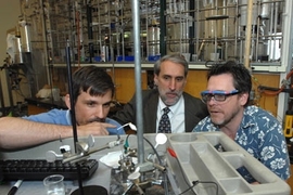 Chemistry professor Jonas Peters, Dan Nocera, Henry Dreyfus Professor of Energy, and Chris Cummins survey Nocera's piece of their solar energy work on artificial photosynthesis in Nocera's lab.