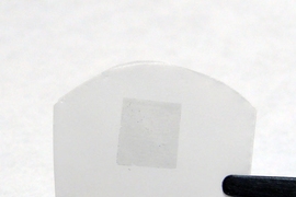 The researchers&#39; membrane, consisting of graphene on a polycarbonate track etch membrane (the graphene is the darker region in the center of the white film). The total membrane is about 2 cm wide by 1 cm tall, while the graphene portion is about 5 mm by 5 mm.