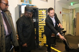 Hugh Herr, director of the Media Lab’s Biomechatronics group, right, shows Sierra Leone President Julius Maada Bio, center, some of the features of his own high-tech prosthetic leg, developed at the lab.