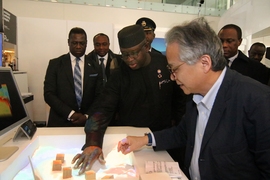 Prof. Hiroshi Ishii, right, Director of the Tangible Media Group and Associate Director of the Media Lab, demonstrates  to Sierra Leone President Julius Bio, center, a system his lab developed for modeling the effects of changes in a landscape.