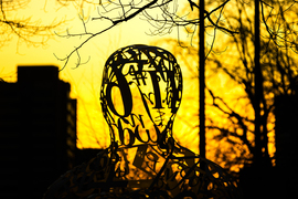 MIT's "The Alchemist" sculpture, with numbers making up the shape of a human head, against a sunset sky