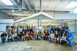 Group photo of about 40 coworkers smiling in large indoor space.