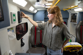 Abigail Schipper presses buttons on a mounted device inside the packed ambulance.