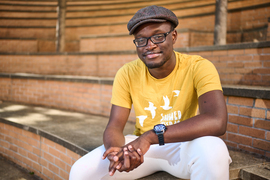 Josh Kuffour smiles while sitting on one of the steps in the amphitheater outside the Stata Center.