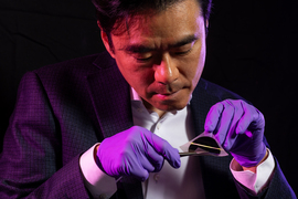 Jeehwan Kim wears purple gloves and inspects a shiny silicon-type wafer.