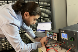 Omid Mortazavi uses a multimeter and another device to test voltages in a lab.