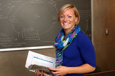 Jillian Wisniewski standing in front of a chalkboard, smiling at the camera