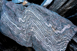 A chunk of split rock has wavy bands of black and white stripes inside.