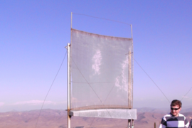 View of one of the test fog collectors set up by the MIT team in Chile, as it gathers water in the white plastic drum.