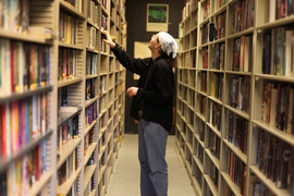 D. W. Rowlands, president and "skinner," goes through the stacks in the society library. The Society strives to acquire every new science-fiction publication for its collection, sometimes obtaining proofs before a book is officially published. 