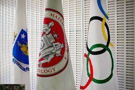 Three flags on poles: Massachusetts state, MIT, and Olympics