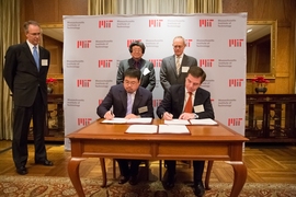 Samuel Tak Lee '62, SM '64 (standing, left) and MIT President L. Rafael Reif look on as Lee's son, Samathur Li, and MIT Executive Vice President and Treasurer Israel Ruiz sign documents related to Lee's $118 million gift to MIT.