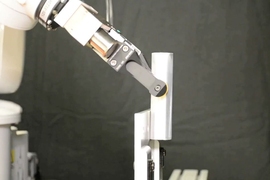 The robot pivots the rod between its fingers by pushing against a bookend. 